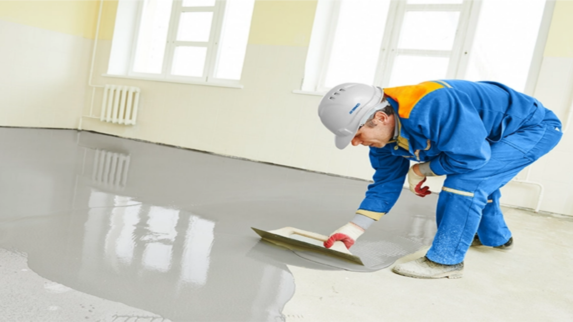 Worker applying self-leveling flooring material.